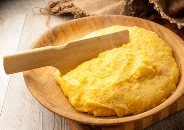 Lombardy cuisine: Traditional polenta served in a wooden bowl with a wooden serving tool.