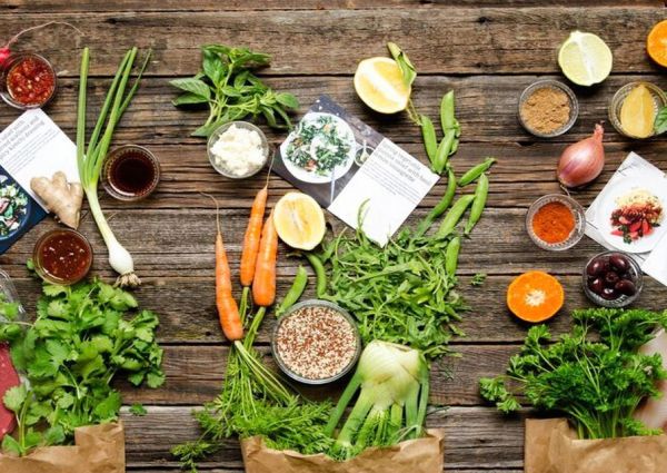 Meal kit ingredients on wood: fresh produce, spices, sauces, and recipe cards for innovative, foodie-friendly cooking.