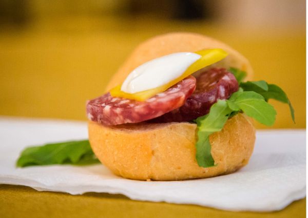 Cacciatore Italiano Panino: Salami sandwich with arugula, cheese, and yellow pepper on a bun. Exotic Italian street food.