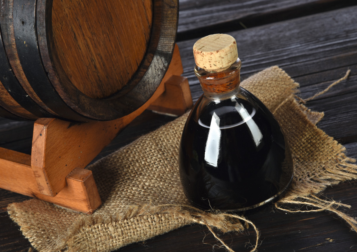 Balsamic vinegar of Modena on a jute canvas and with barrel behind