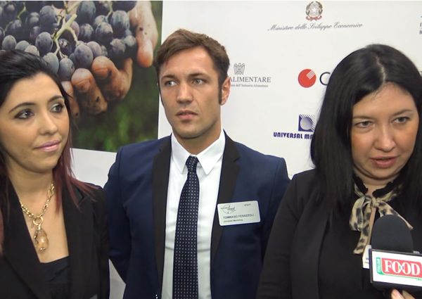 Italian Food Awards USA 2019: Three people in front of sponsor logos.