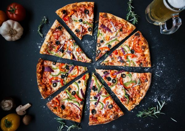 Sliced frozen pizza with peppers, olives, and onions. Italian food, ready to eat.