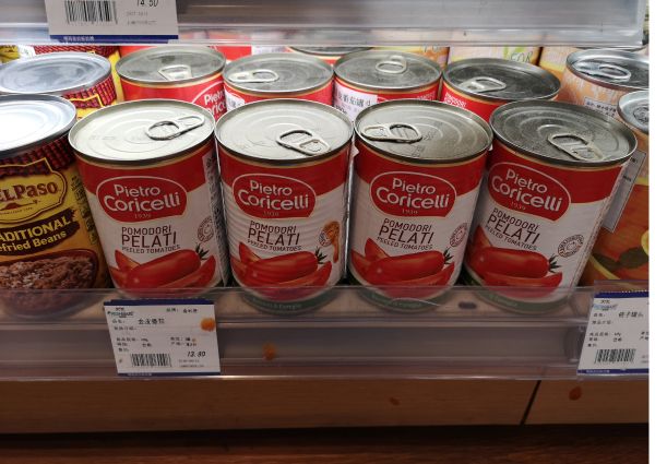 Canned Pietro Coricelli peeled tomatoes on a shelf in Shanghai. Fresh Mart grocery store. High-end shopping tour.