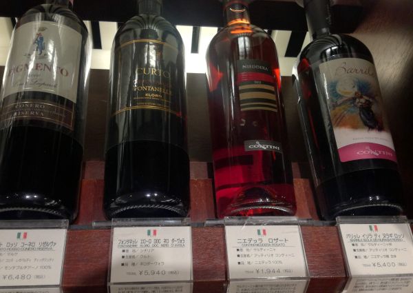 Bottles of Italian wine on display in a Tokyo store: Conero Riserva, Nero d'Avola, Nieddera, and Barrile. Italian F&B.