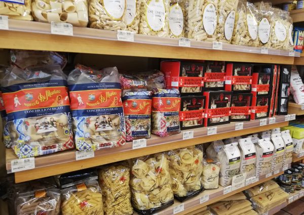Di Bruno Bros. pasta selection. Shelves stocked with various pasta shapes and brands. Italian food market.