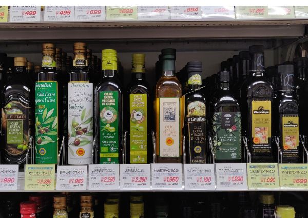 Italian olive oil selection in Osaka, Japan. Shelves of extra virgin olive oil bottles with price tags. Food import.