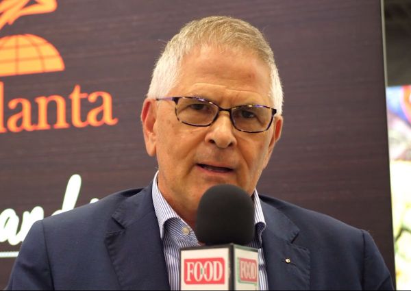 Agriform at SFFS: Man with glasses speaking into a microphone with FOOD logo. Asiago cheese promotion.