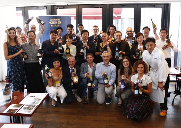 Group poses with Prosecco DOC bottles in Japan. Wine tasting event, promoting Italian sparkling wine.