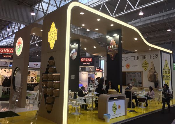 Grana Padano cheese booth at trade show. Italian cheese display with seating area. Food industry event.