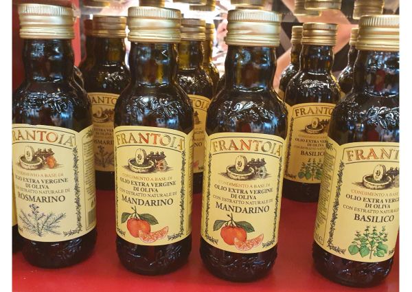 Frantoia Italian olive oil bottles with mandarin, rosemary, and basil flavors at Di Gennaro's deli.