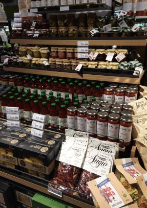 Italian food products on Migros store shelves. Pasta, sauces, and preserved vegetables.