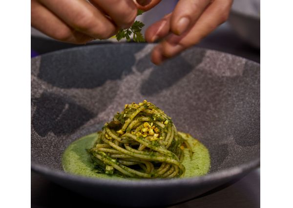 Barilla Master of Pasta: Chef garnishing pasta with green sauce. Fine dining pasta dish.