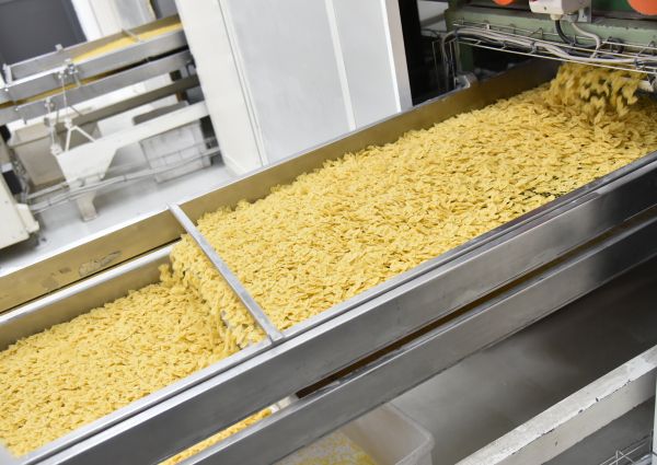 Farfalle pasta production line at Pasta di Gragnano PGI factory. Fresh pasta on conveyor belt.