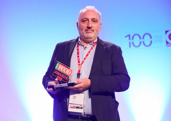Italian Food Awards 2019 winner. Man holding award on stage. Italian cuisine.