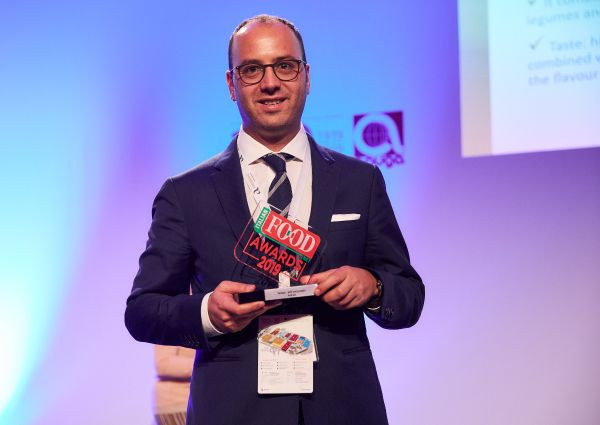 Italian Food Awards 2019 winner. Man in suit holding award. Food industry recognition.