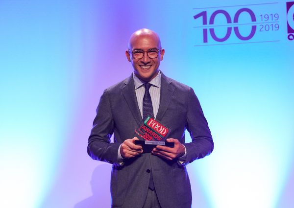 Italian Food Awards 2019 winner. Man in suit holding award, smiling.