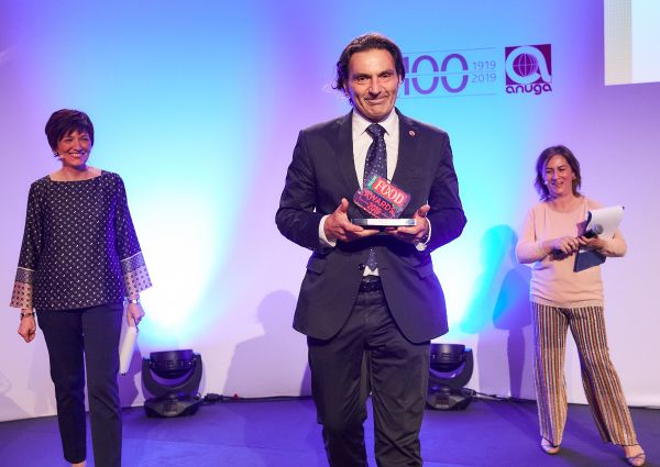 Italian Food Awards 2019 winner on stage holding award. Two women stand on either side of the man.