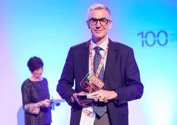Italian Food Awards 2019 winner. Man holding award on stage. Italian cuisine recognition.