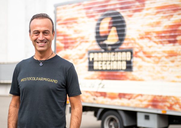 Man in #iostocolparmigiano shirt, Parmigiano Reggiano truck. Italy prepares for US tariffs.