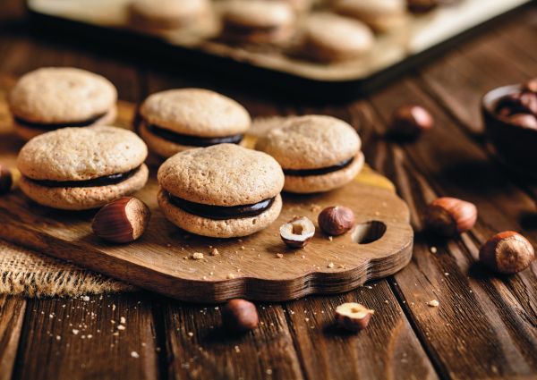 Piedmont specialties: Hazelnut cookies filled with chocolate cream on a wooden board. Italian dessert.