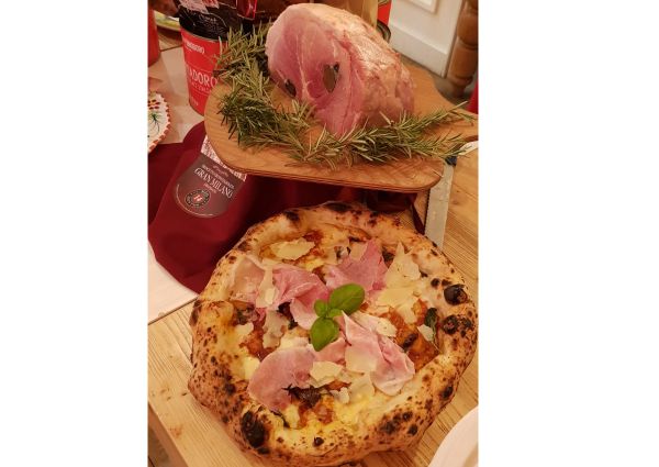 Rovagnati & Rossopomodoro pizza event. Pizza with prosciutto and cheese, plus a ham roast on a wooden board.