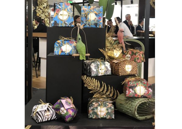 Display of Panettone Muzzi Italian cakes in decorative boxes with animal and floral prints at a trade show.