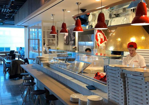 Rossopomodoro Eataly Canada: Interior view of the pizza restaurant with pizza chef, oven, and red pendant lights.
