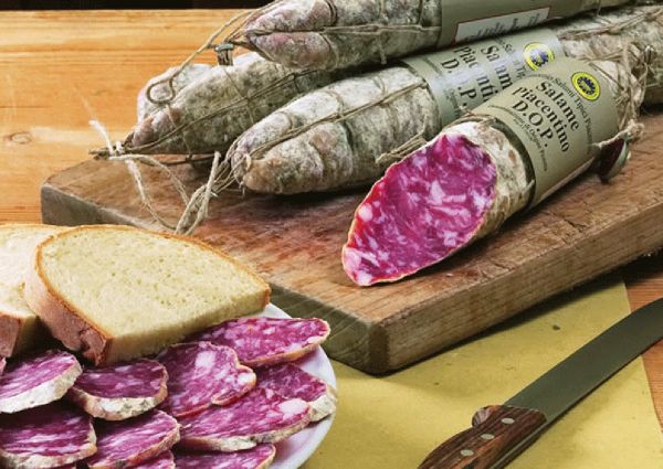 Salame Piacentino DOP. Italian PDO salami with bread on a wooden board. Cured meat product.