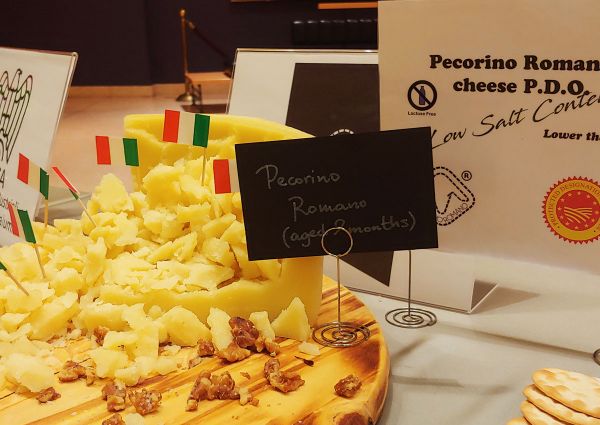 Pecorino Romano cheese on a wooden board with Italian flags. Aged 8 months. Geographical indication. US consumers want safety.