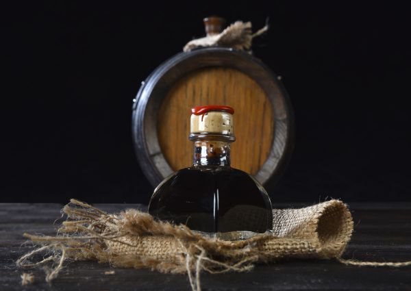Gourmet balsamic vinegar in glass bottle with barrel background. Italian food.