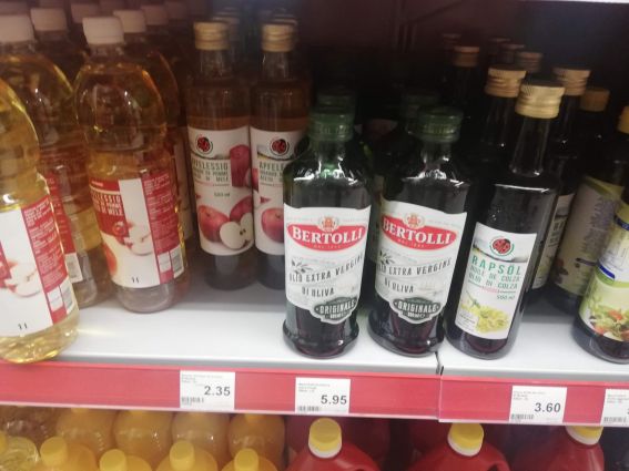 Denner Market shelf with Bertolli extra virgin olive oil, apple vinegar, and rapeseed oil.