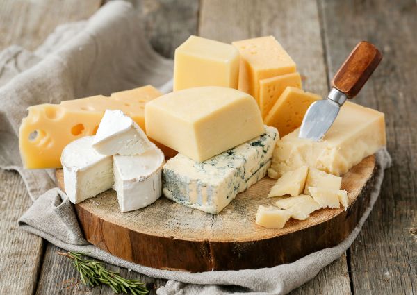 Assorted Italian PDO cheeses: Parmesan, Brie, and Blue cheese on a wooden board.