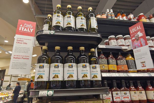 Italian olive oils at Whole Foods. Shelves of 365 brand olive oil bottles. Grocery store product display.