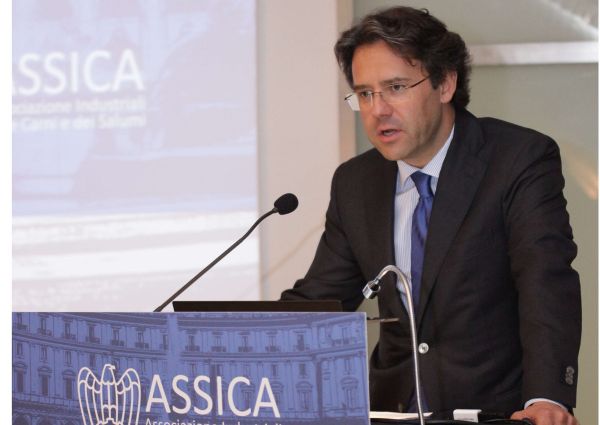 ASSICA speaker discusses Italy's cured meat exports. Man in suit at podium.