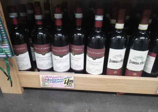 Trader Joe's Italian wine selection: Montepulciano d'Abruzzo and Barbera d'Asti red wine bottles on shelves.