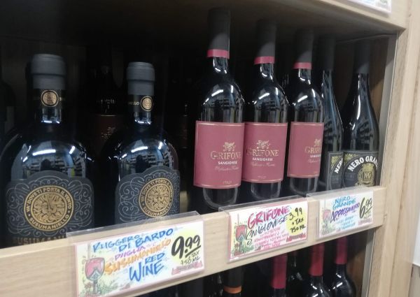 Trader Joe's Italian wine selection: Sangiovese, Susumaniello, and Nero Grande bottles on a wooden shelf.