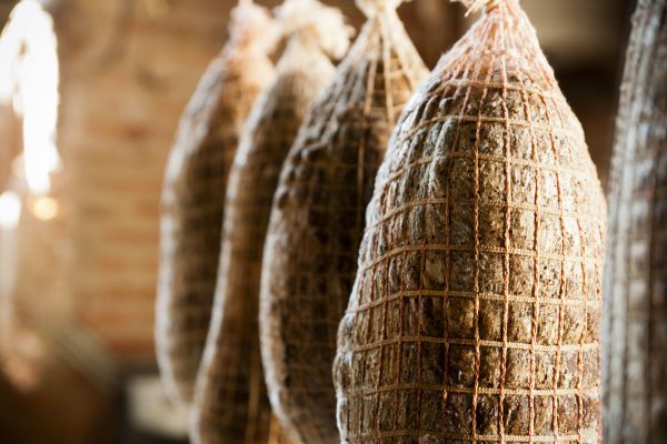 Italian salumi. Cured meats hanging, netted. Traditional food.