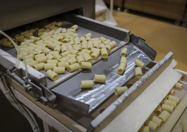 Pasta di Gragnano PGI: Mezze Penne pasta on a conveyor belt in a pasta factory.