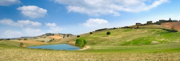 Modena area landscape. Rolling hills, blue sky, and lake. Prosciutto di Modena PDO production area.