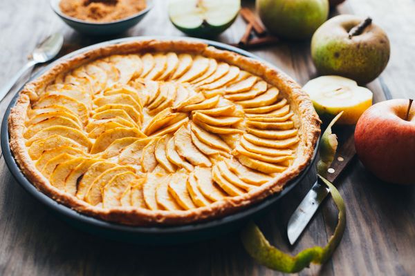 Apple cake for World Baking Day. Homemade apple pie with sliced apples on a wooden table.