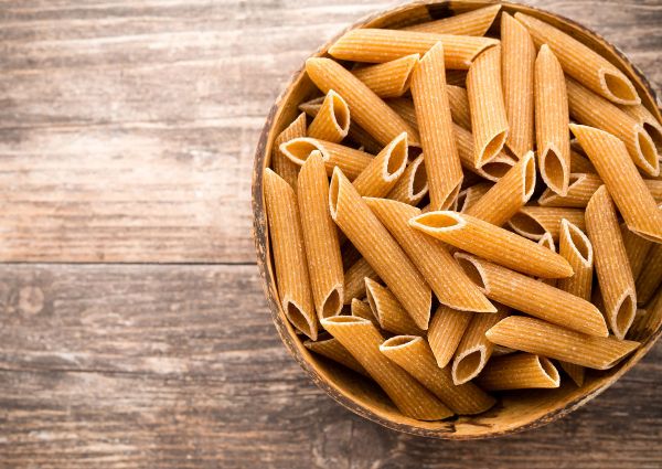 Whole wheat penne pasta in a bowl. Italian pasta industry.