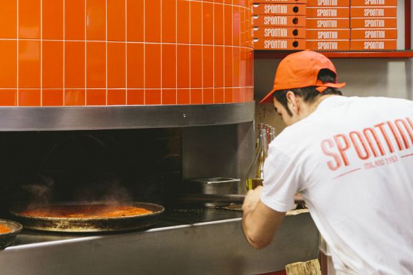 Spontini pizza chef preparing pizza in oven. Spontini plans new stores.