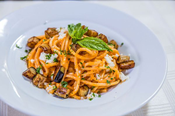 Bucatini Siciliana pasta dish. Italian cuisine with tomato sauce, eggplant, ricotta cheese, and basil. Made in Italy of the Caribbean.
