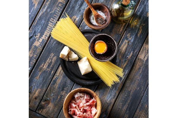Carbonara ingredients. Spaghetti, egg yolk, cheese, olive oil, bacon, salt and pepper on a wooden background.