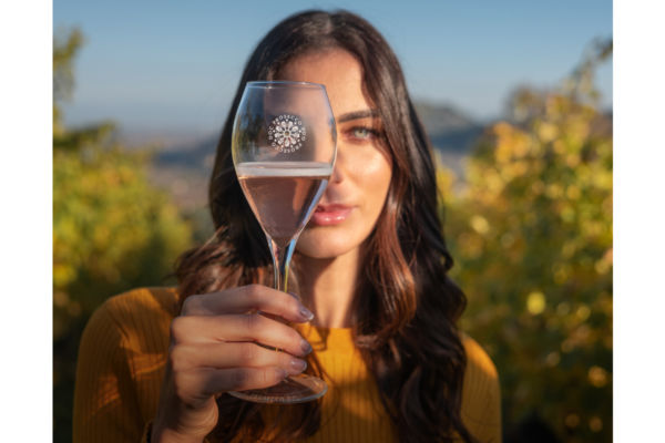 Woman holding Prosecco DOC Rosé glass. Sparkling rosé wine with vineyard background.