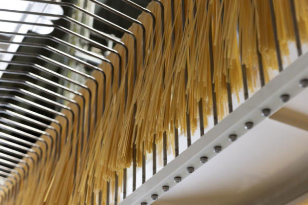 Barilla Al Bronzo pasta hanging on a production line, showing the pasta-making process.