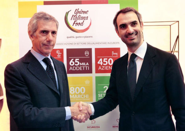 Italian Food Innovation: Two men shake hands in front of Unione Italiana Food banner.