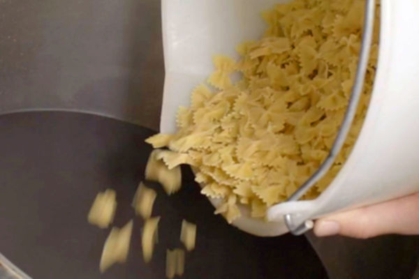 Farfalle pasta being poured. Berruto pasta for anti-waste beer production. Food industry concept.