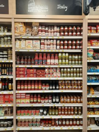 Carrefour supermarket shelf with Italian food brands: pasta, tomato sauce, pesto, and snacks.