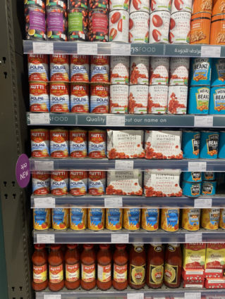 Spinneys Dubai grocery shelf with Italian A brands: Mutti passata, Heinz beans, chopped tomatoes, and tomato juice cans.